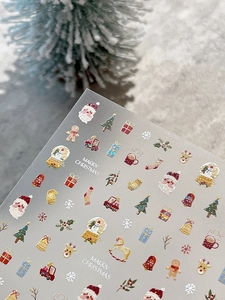 Macro shot of 3D Christmas nail stickers with Santa, tree, and Merry Christmas text