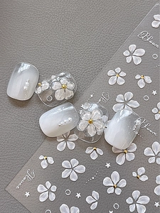 Detail of 3D embossed floral nail stickers with white flowers and gold beads on leather background