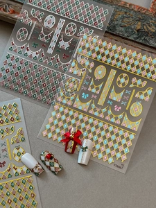 Detail of festive Christmas plaid nail art stickers with gold foil accents and bow patterns