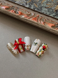 Detailed view of Christmas nail art featuring red bows and gold snowflake relief