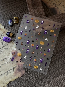 3D relief Halloween nail stickers with pumpkins, skulls, and crosses on dark wood background