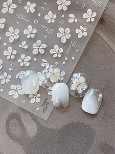 Macro view of 3D embossed white flower nail stickers with gold beads and pearl accents