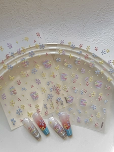 Dettaglio di adesivi 3D per unghie con motivi di stelle, lune e fiori colorati
