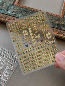 Close-up of gold embossed Christmas nail stickers with red and green plaid patterns