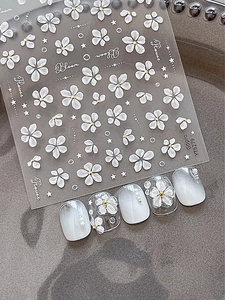 Macro view of 5D embossed white floral nail art stickers with golden center accents