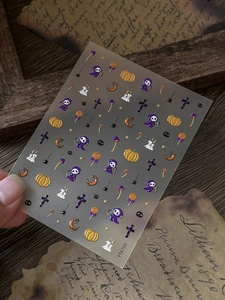 Macro detail of Halloween nail art stickers with embossed grim reaper and pumpkin motifs