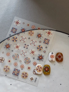 Dettaglio di adesivi per unghie bohémien con motivi floreali geometrici e bordi dorati