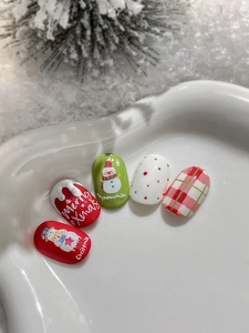 Detail of Christmas nail stickers featuring embossed snowmen and plaid patterns on a dish