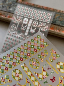 Macro view of Christmas nail stickers with gold foil embossed plaid and snowflake patterns