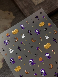Close-up of 3D embossed Halloween nail stickers with pumpkins and purple reaper designs