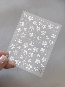 Detailed view of white floral nail decals with gold accents and Bloom text YT5279