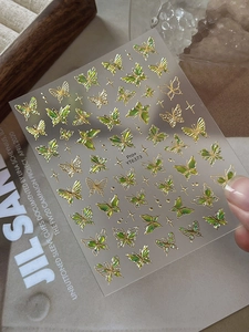 Macro shot of YT6373 gold foil butterfly nail stickers with iridescent green shimmer