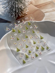 Gros plan d'autocollants 3D pour ongles sapin de Noël avec étoiles sur plateau blanc