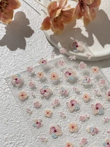 Detailed view of 5D embossed floral nail stickers on textured stone with soft shadows