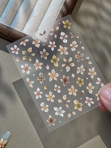 Gros plan de stickers à ongles fleurs 3D avec détails de pétales gaufrés dorés