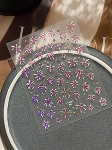 Close-up of luxury firework nail art stickers with glitter effects on grey display