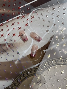 Detail of four-pointed star nail stickers with rhinestones on purple gradient nails