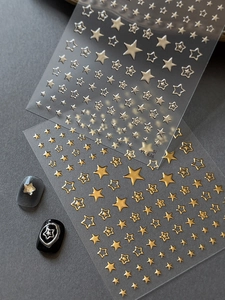 Détail d'autocollants 3D étoiles or et argent montrant diverses tailles sur des ongles