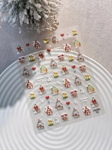Close-up of Christmas House nail stickers with snowmen and cottages on a white ceramic plate