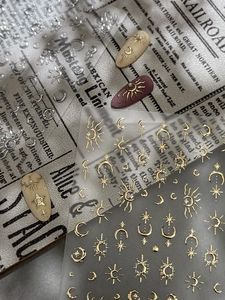 Macro view of gold celestial nail stickers featuring sun and moon embossed details