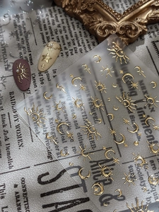 Macro detail of 3D gold sun and moon nail stickers applied on various nail colors