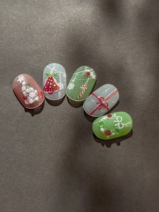 Dettaglio di nail art natalizia in rilievo 3D con campanelli e ciondoli ad albero