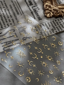 Detail showing golden embossed sun and moon nail stickers on vintage paper background
