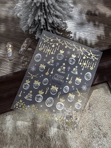 Detail of Christmas nail stickers with gold and white snowflakes on wood surface