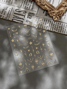 Macro shot of gold celestial nail stickers featuring metallic sun and moon patterns