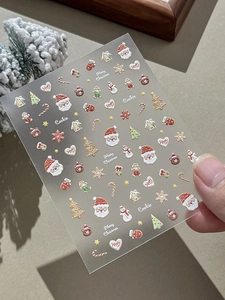 Detailed Christmas nail art stickers featuring Santa, trees, and cookies on a sheet