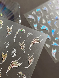 Macro shot of laser butterfly nail stickers with holographic floral pattern details