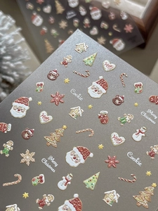 Detailed macro of 3D embossed Christmas nail stickers featuring Santa and gingerbread motifs