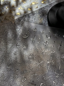 Macro shot of metallic moon and star nail art stickers with silver and gold relief details