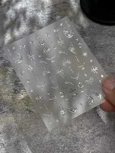 Detail of silver metallic star and moon nail stickers with butterfly and sun designs
