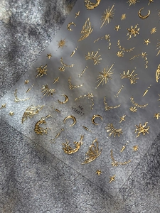 Macro detail of gold metallic nail stickers featuring vintage moon and star relief designs