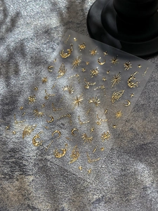 Detail of gold celestial nail stickers featuring sun, moon, and stars patterns