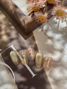 Détails d'ongles cat eye champagne avec breloques papillons 3D colorées et dorées