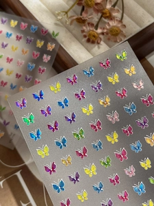 Détails d'autocollants papillons colorés pour ongles avec paillettes sur fond floral