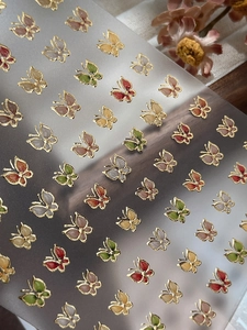 Détail macro de stickers papillon colorés pour ongles avec bordures dorées en relief
