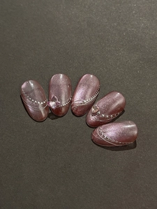 Detail of luxury purple cat eye press-on nails with silver curves and 3D butterfly charms