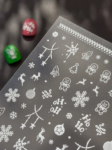 Macro shot of 5D embossed Christmas nail stickers with white snowflakes and reindeer