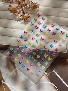 Détail macro de stickers ongles papillons colorés 3D sur un plateau en velours beige