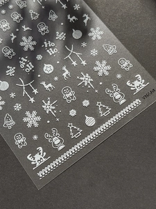 Detailed macro of 5D embossed Christmas nail stickers with snowflakes and reindeer