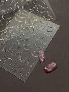 Detail of gold and silver metallic chain nail art stickers on dark purple cat-eye nails