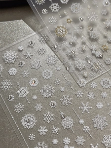 Detail of 3D embossed Christmas snowflake nail stickers with gold accents and rhinestones