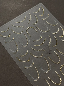 Macro detail of gold metal bead nail stickers with French arc patterns on model YT5251