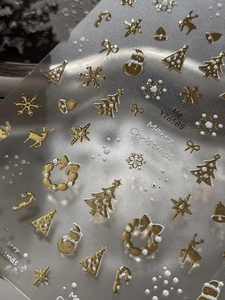 Macro shot of 3D gold and white embossed Christmas tree and snowflake nail stickers