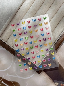 Détail de stickers à ongles papillons colorés avec contours blancs sur boîte en bois