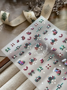 Detailed 5D relief Christmas nail stickers with red bows and holly on beige cloth