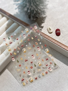 Christmas nail art stickers featuring Santa, reindeer, and snowflakes on a beige backdrop